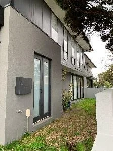 Modern two-story house with large windows and gray exterior walls.