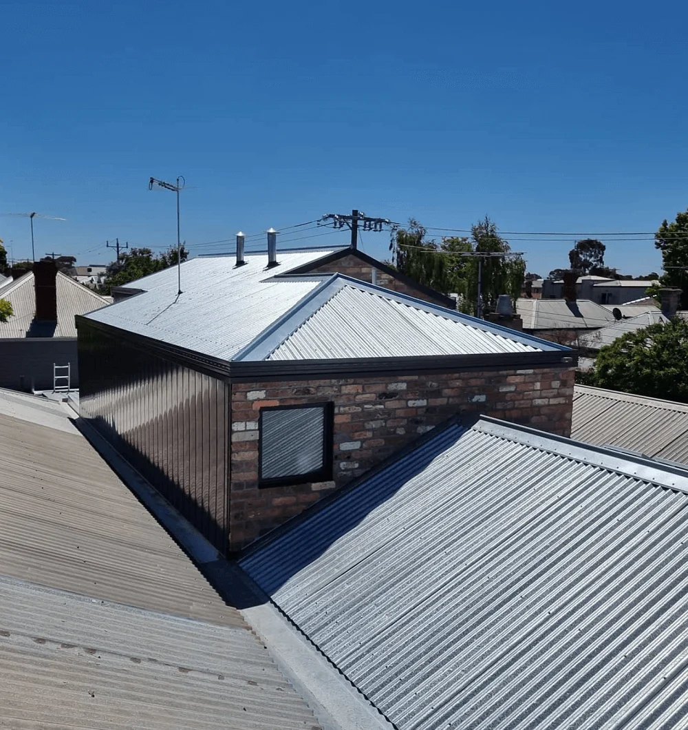 Metal roofs on residential homes under a clear blue sky.