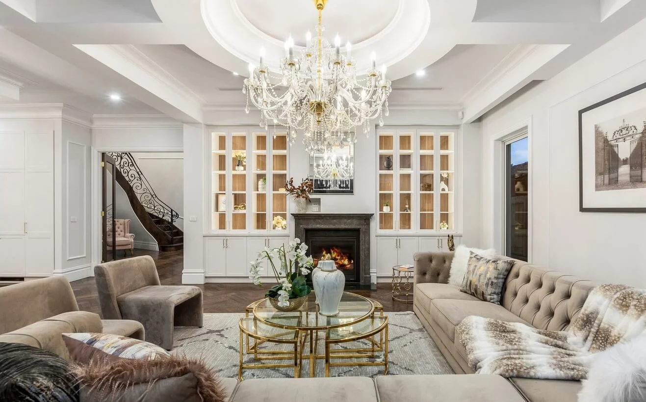 Elegant living room with chandelier, fireplace, and glass coffee table.