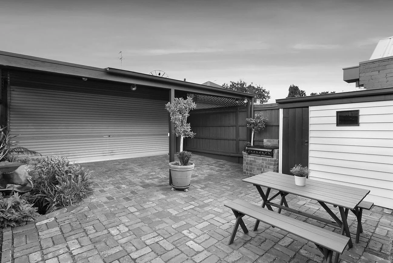 Black and white image of a suburban house with a garden.