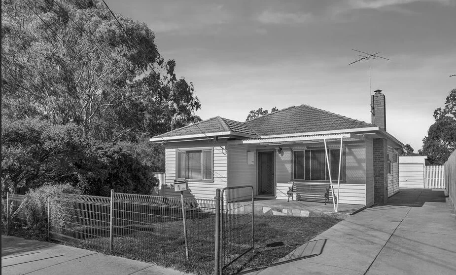 Black and white image of a suburban house with a garden.