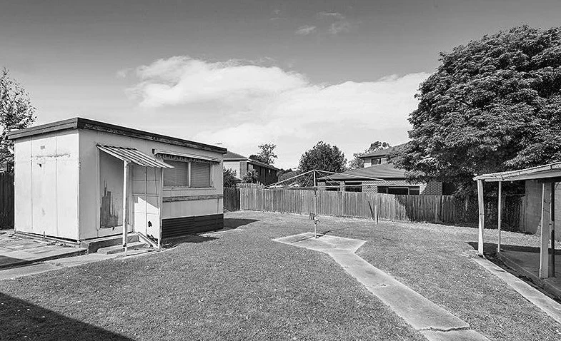 Black and white image of a suburban house with a garden.
