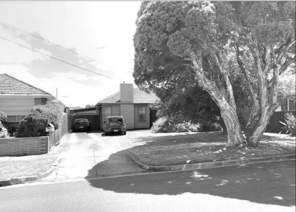 Black and white image of a suburban house with a garden.