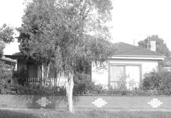 Black and white image of a suburban house with a garden.