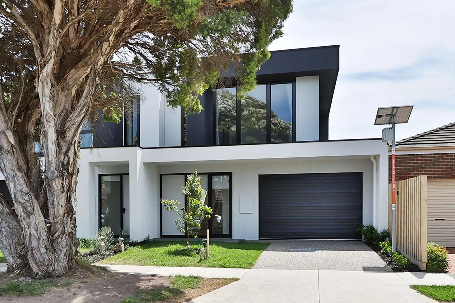 Modern two-story house with large windows and a black garage door.